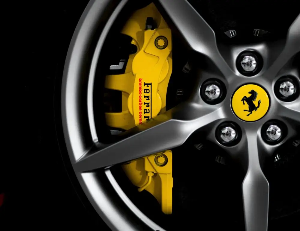 Close-up of a silver alloy wheel with a yellow Ferrari brake calliper and prancing horse emblem at the centre—a stunning detail any Ferrari enthusiast or Ferrari Insurance policyholder would admire.