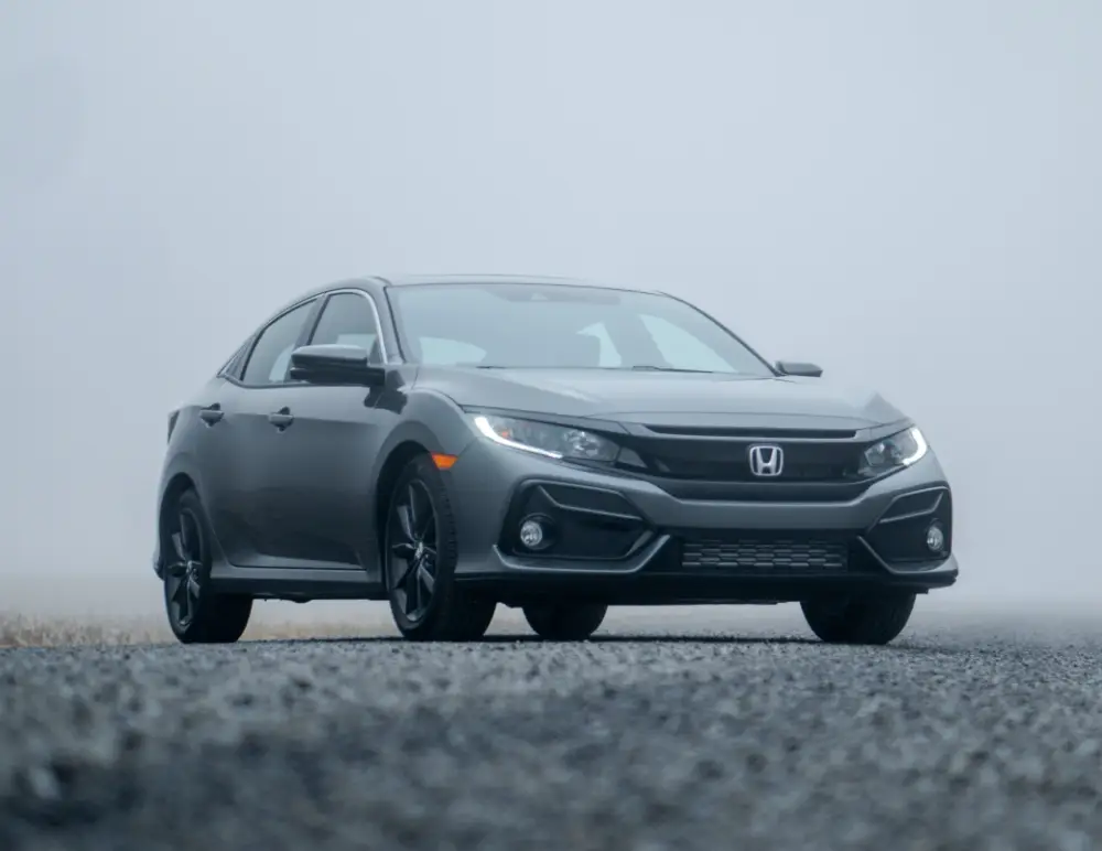 A grey Honda saloon, perfect for Honda insurance cover, is parked on a gravel surface with a foggy, overcast background, creating a moody and atmospheric scene.