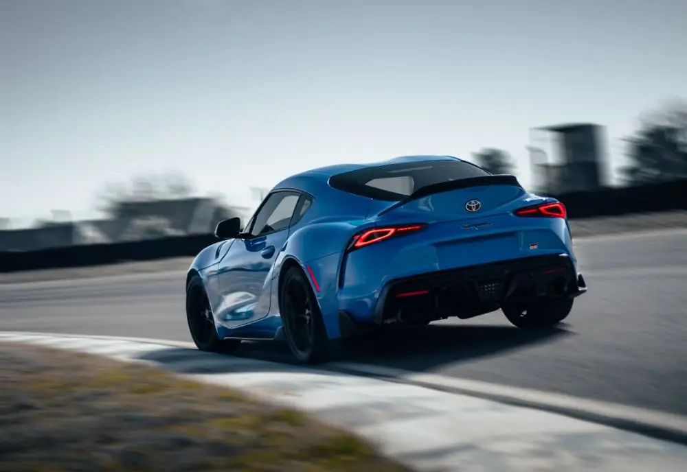 A blue sports car, likely a Toyota Supra, takes a sharp turn on a racetrack with blurred background, emphasising its speed and agility—an exhilarating moment where Toyota Insurance brings added peace of mind.