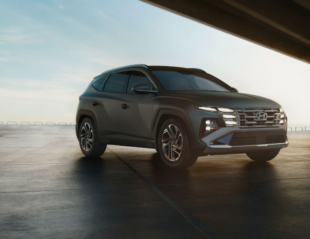 A sleek Hyundai SUV is parked on a smooth concrete surface under a clear sky, angled to showcase its bold front grille, sharp body lines, and distinctive LED headlights.